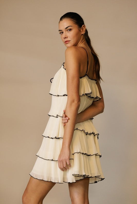 RARA Boutique tiered ruffle plisse mini dress with front tie, featuring feminine layered ruffles and a stylish silhouette.