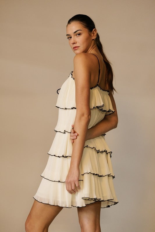 RARA Boutique tiered ruffle plisse mini dress with front tie, featuring feminine layered ruffles and a stylish silhouette.