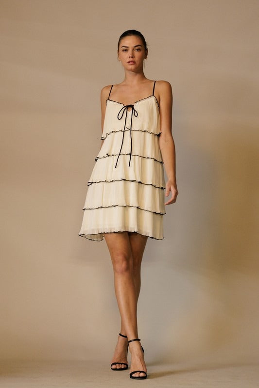 RARA Boutique tiered ruffle plisse mini dress with front tie, featuring a stylish layered design and feminine silhouette.