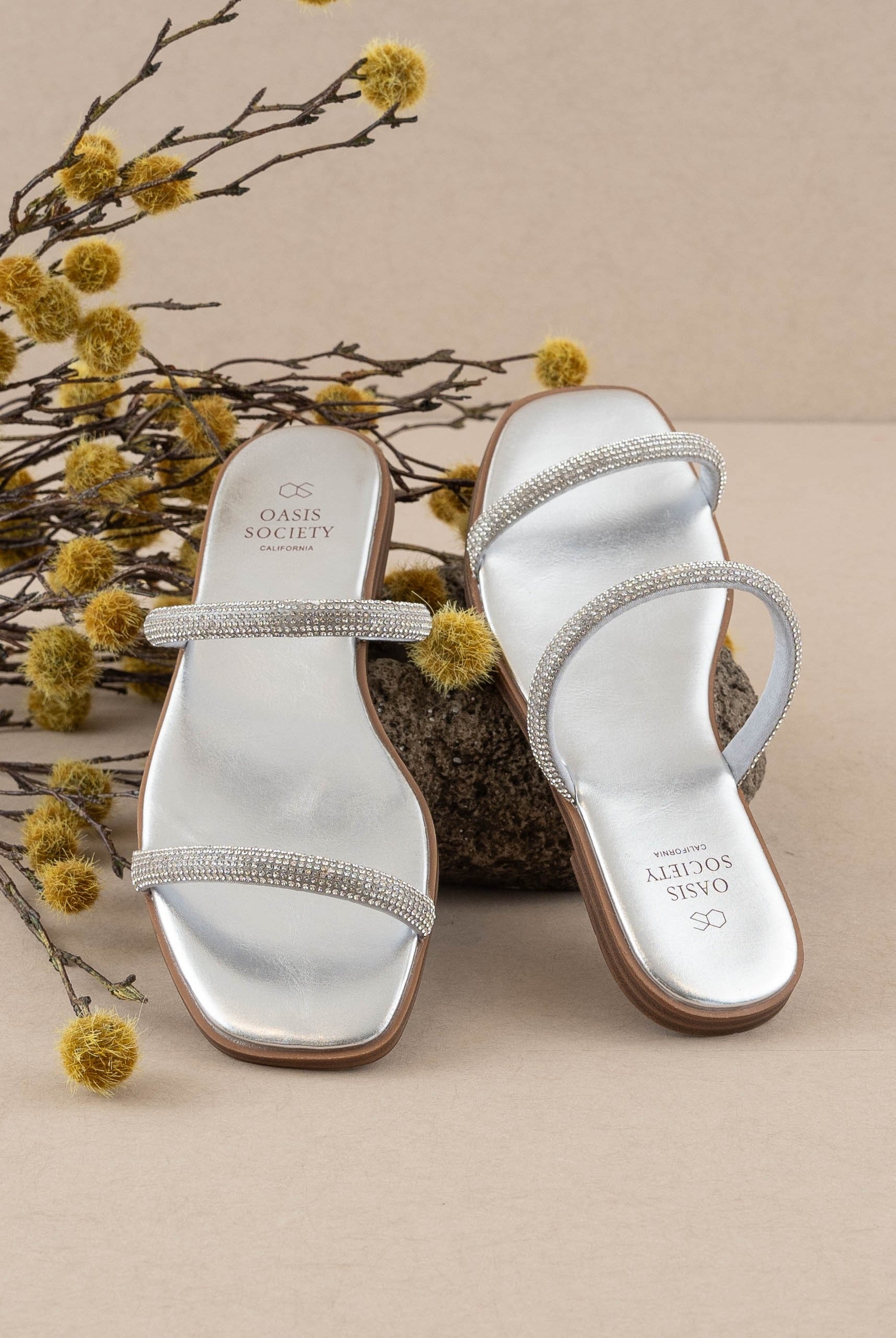 Rara Boutique rhinestone strappy flat slide sandals with thin straps and rhinestone embellishments on a neutral background.