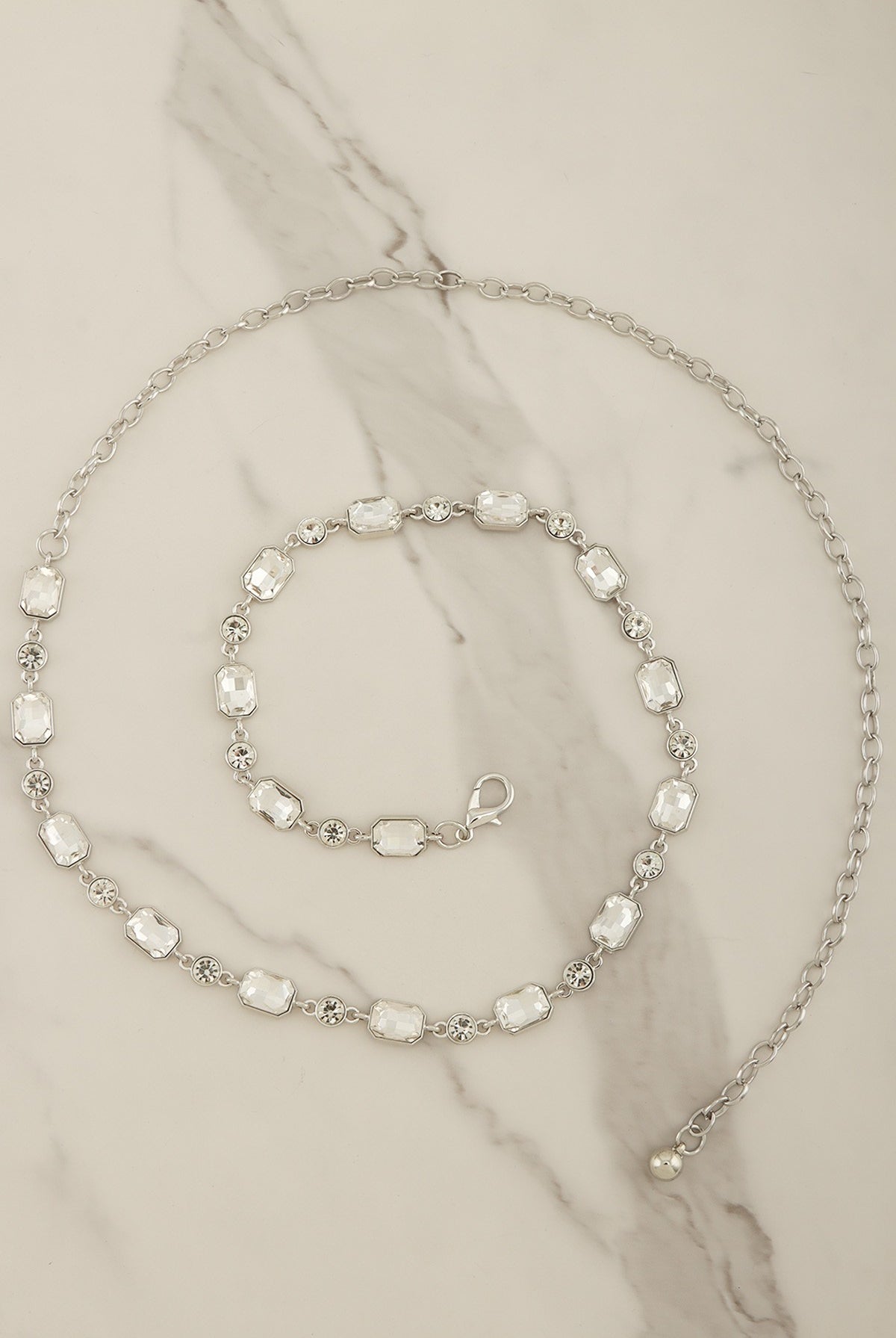 Emerald-cut crystal chain belt with silver-tone links, stylish accessory from RARA Boutique, showcasing its elegant design and sparkling crystals.