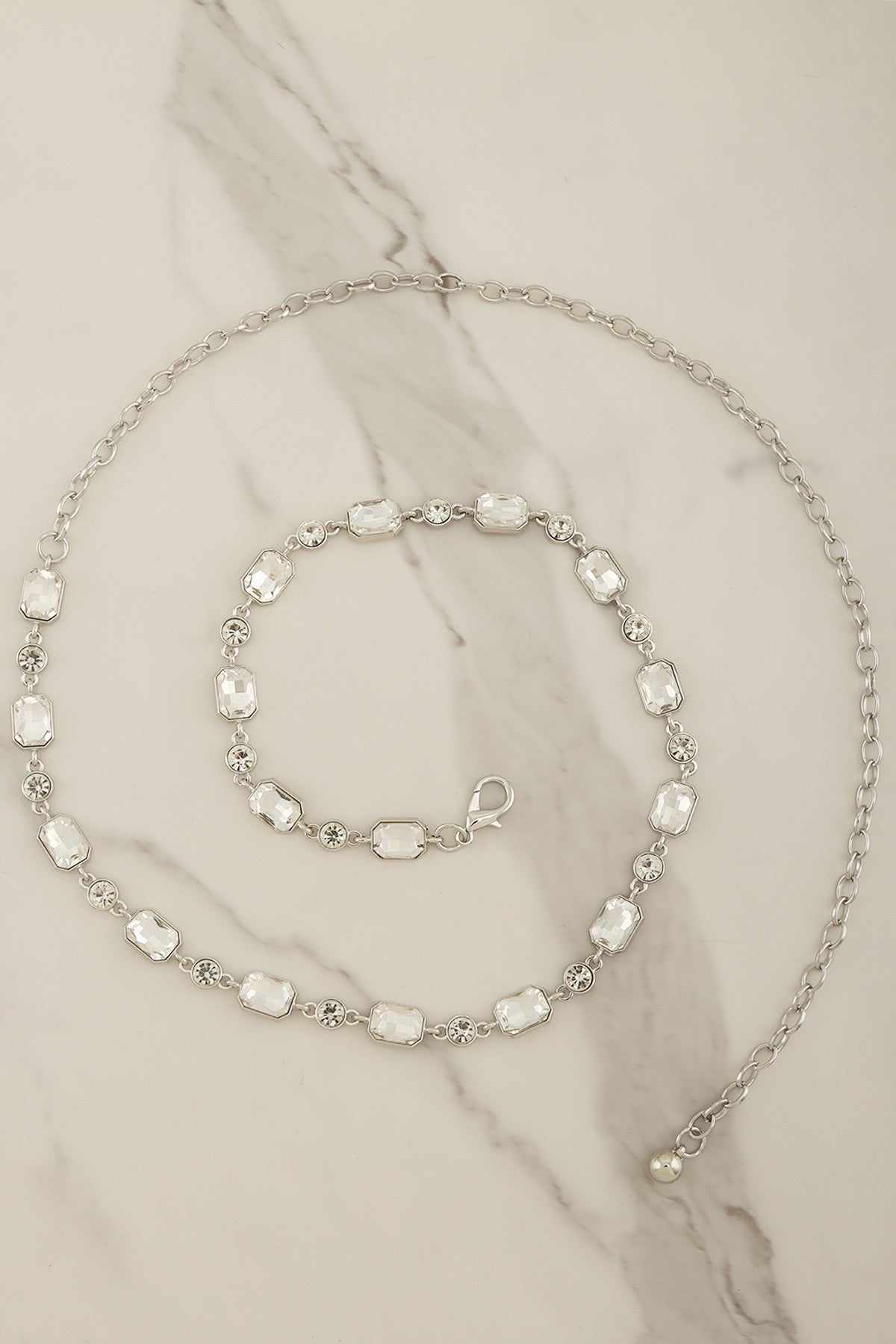 Emerald-cut crystal chain belt with silver-tone links, stylish accessory from RARA Boutique, showcasing its elegant design and sparkling crystals.