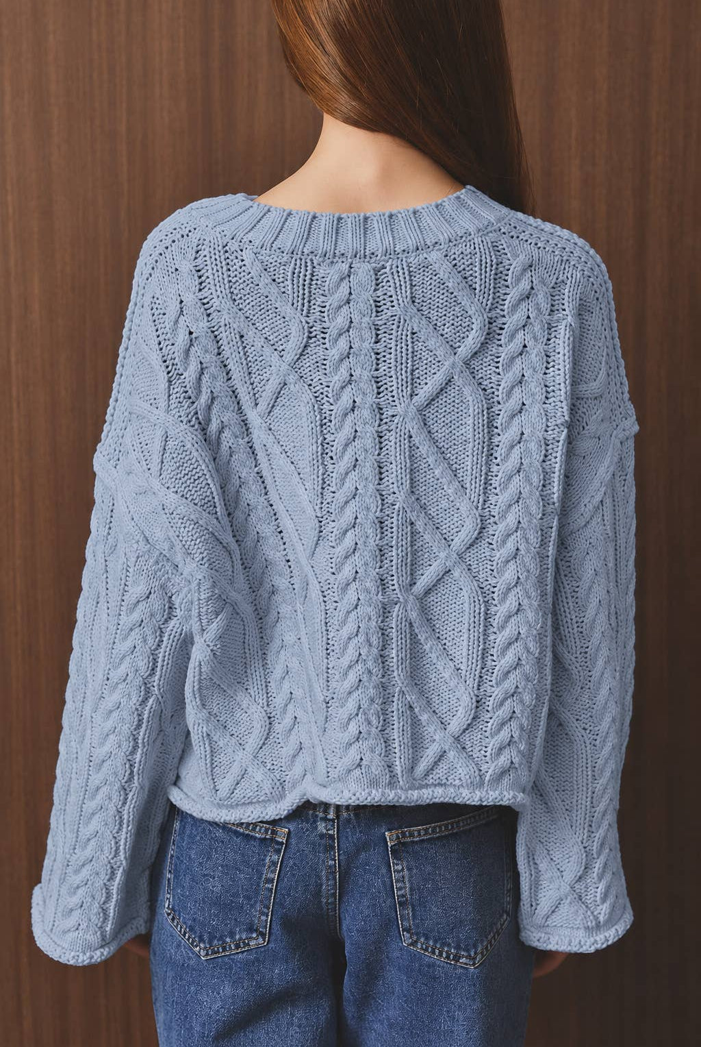 LE LIS oversized cropped cable knit sweater featuring chunky knit texture and relaxed fit, displayed on a hanger.