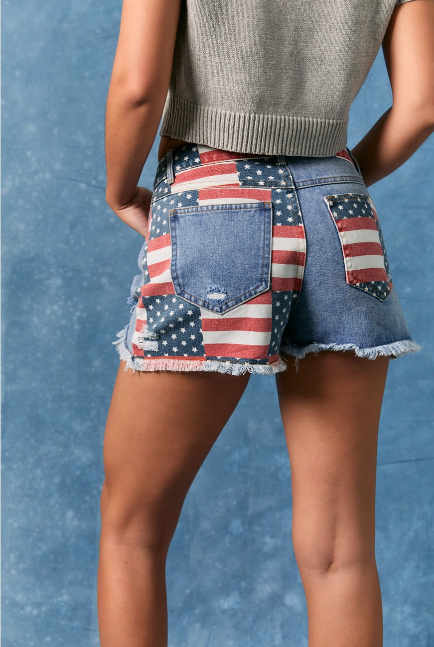 American flag patchwork denim shorts by Le Lis featuring distressed details and frayed hems, styled with casual summer fashion.