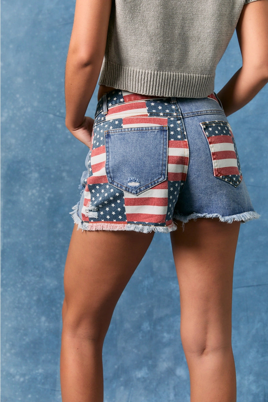 American flag patchwork denim shorts by Le Lis featuring distressed details and frayed hems, styled with casual summer fashion.
