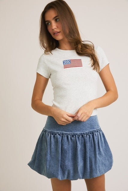 Rara Boutique embroidered American flag ribbed baby tee with short sleeves and patriotic star detail on white fabric.