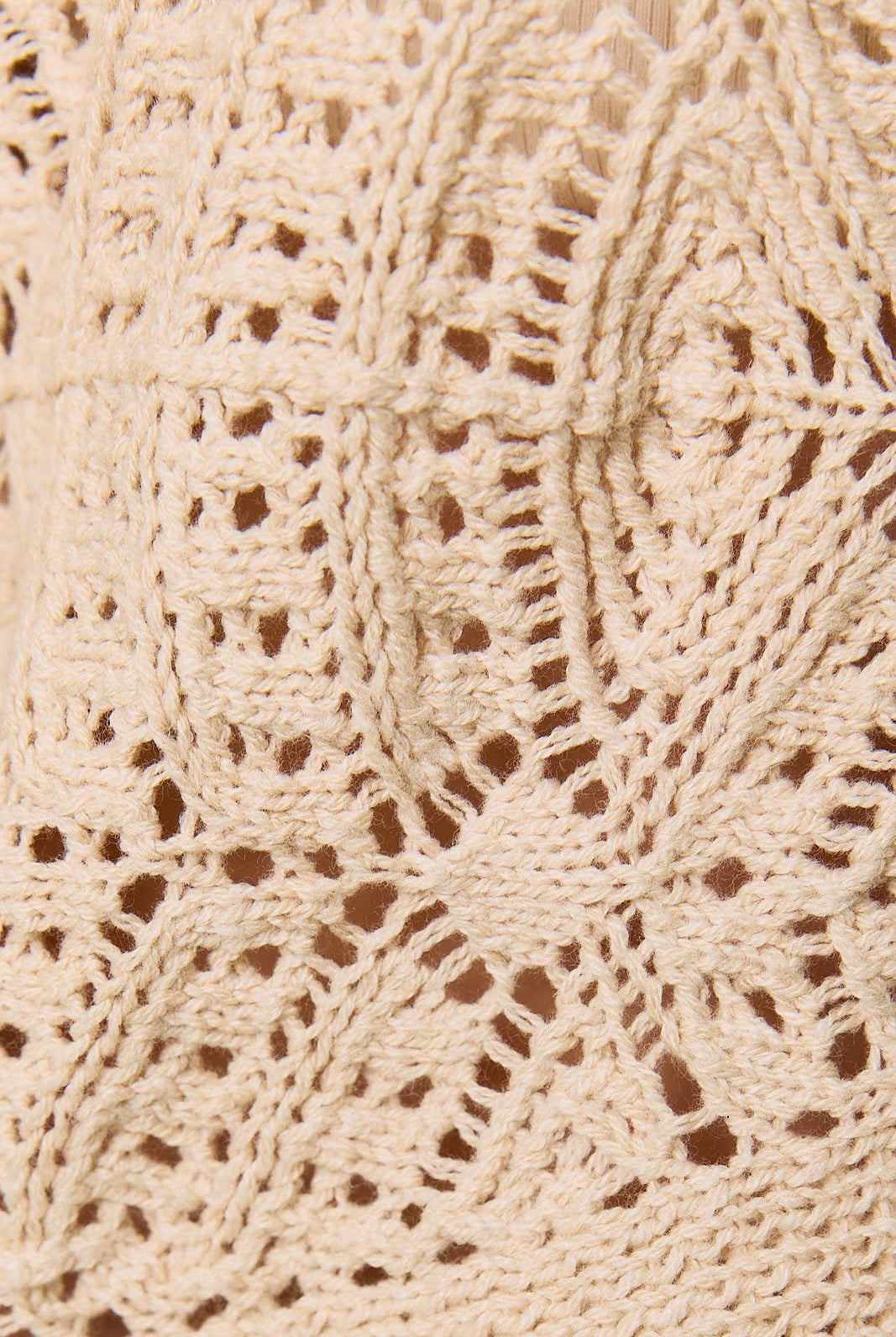 Long sleeve crochet cardigan by LE LIS, featuring intricate knit pattern and button closure, displayed on a neutral background.