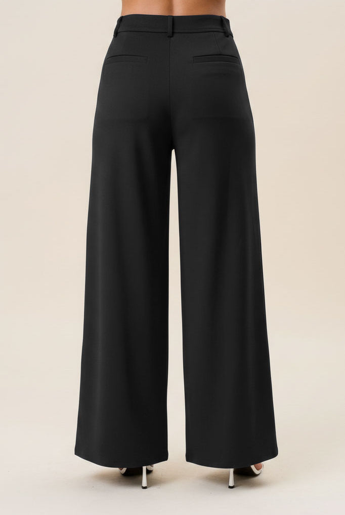Black high waist tailored wide-leg trousers by RARA Boutique, made of smooth fabric with a fitted waistband and flowing leg design.