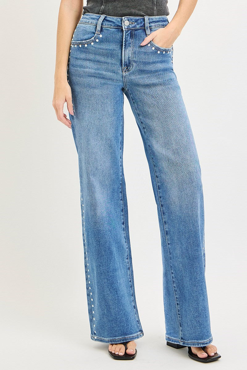 Medium wash Risen studded wide-leg high-rise jeans with distressed details and belt loops, displayed on a hanger.