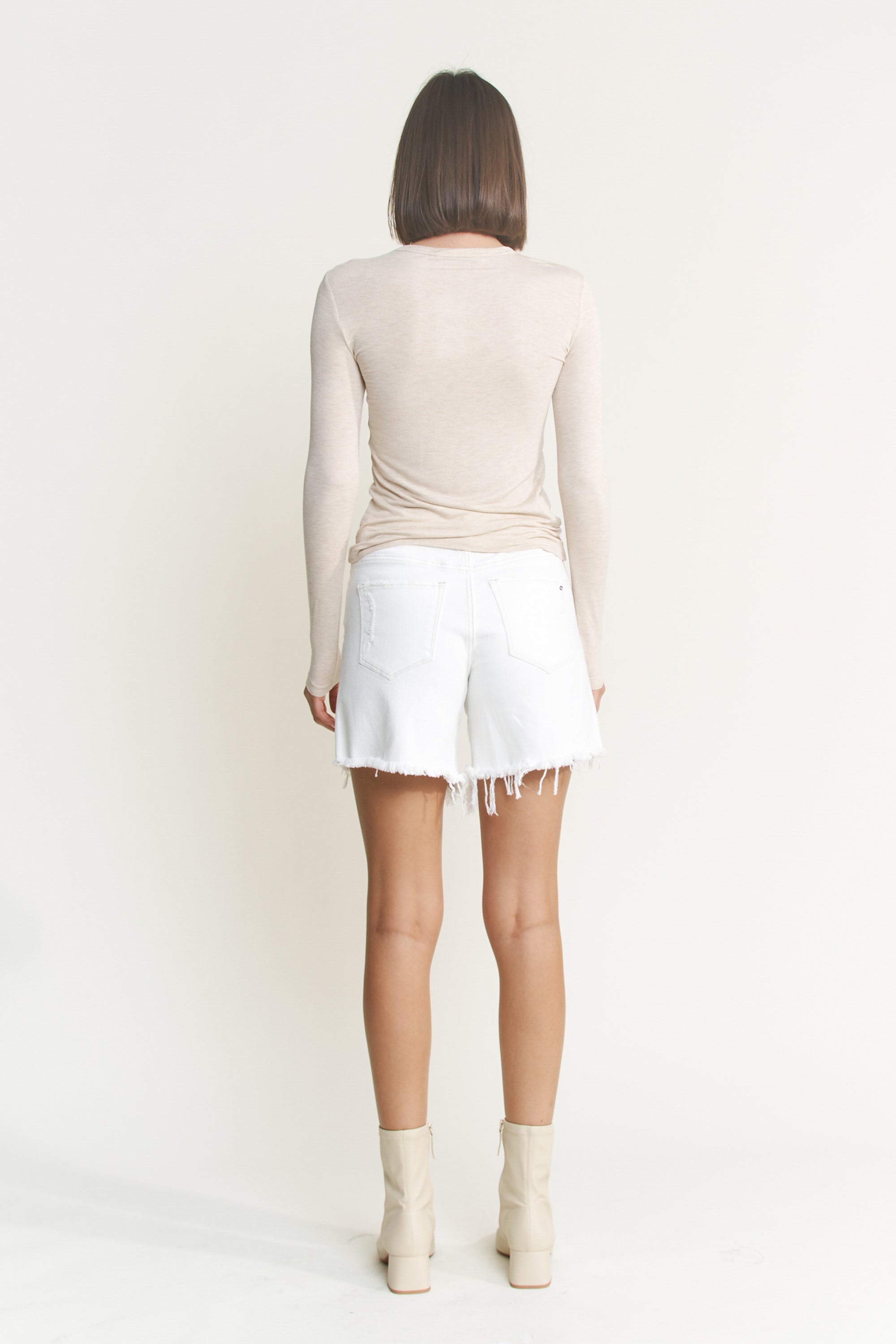 Mid-thigh length high rise raw hem denim shorts by RARA Boutique, featuring distressed detailing and classic blue denim fabric.