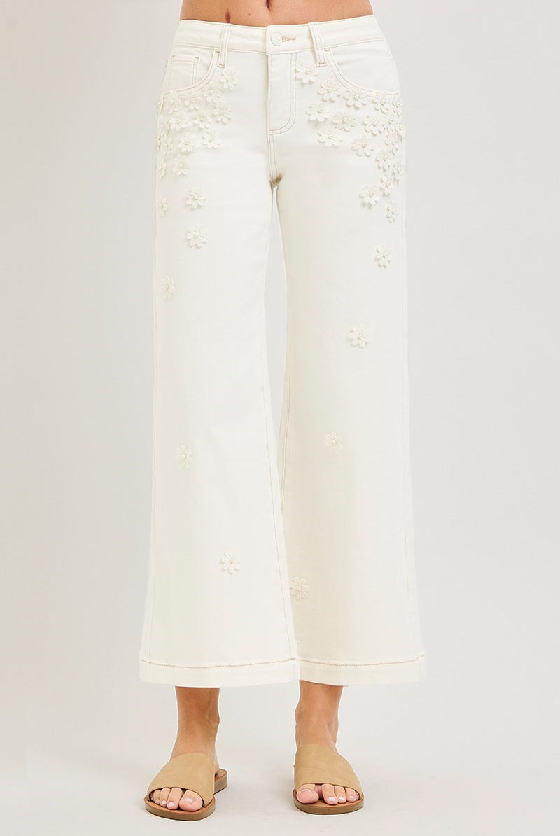 Cream wide-leg cropped jeans with 3D flower and pearl embellishments by RARA Boutique, showcasing detailed floral and pearl accents.
