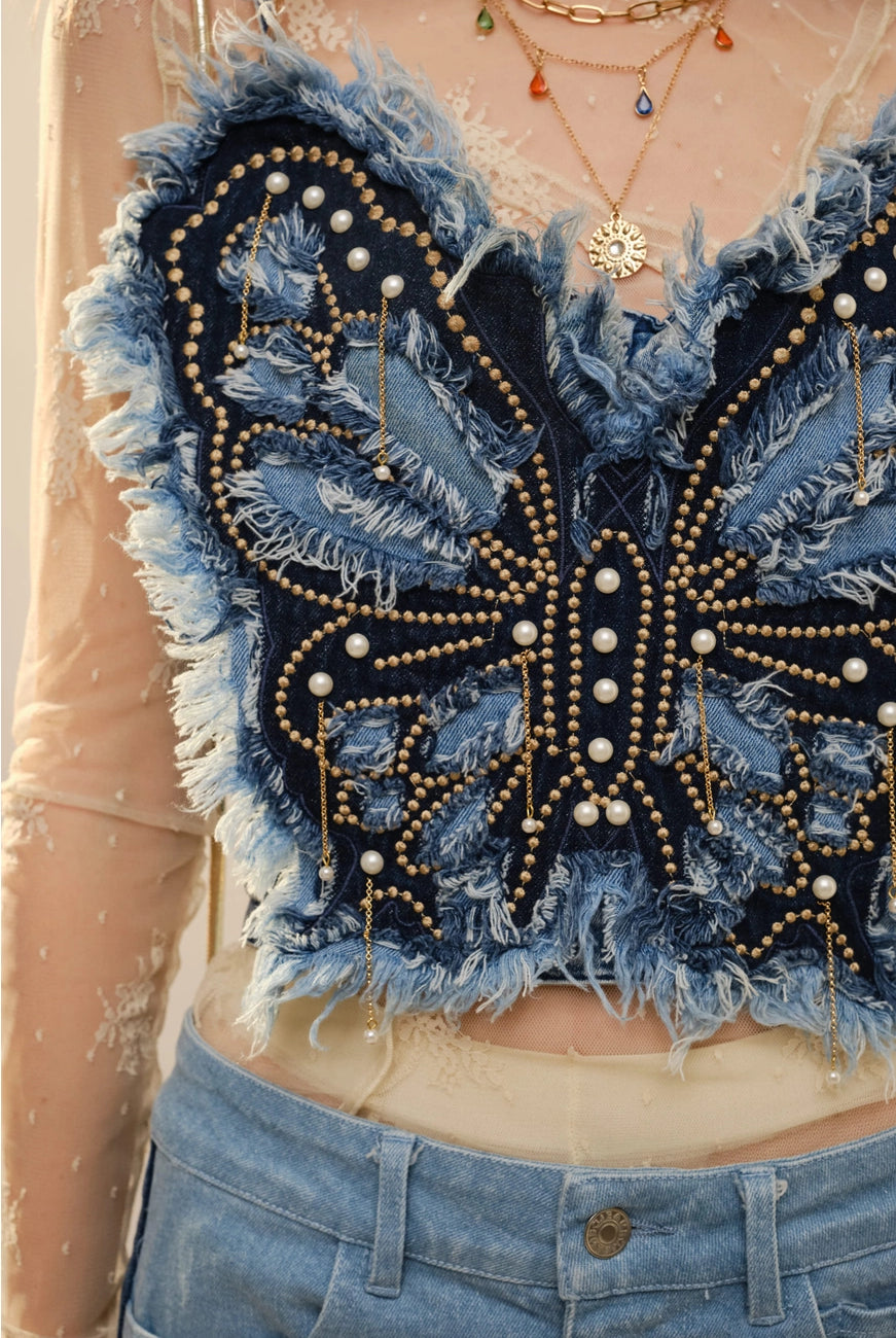 Blue denim corset top with butterfly embellishments, stylish blouse from RARA Boutique, detailed close-up of fabric and decorative butterflies.