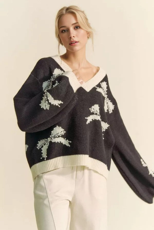 Cream-colored sweater with pearl-studded bow accents, balloon sleeves, and a V-neck, by RARA Boutique.