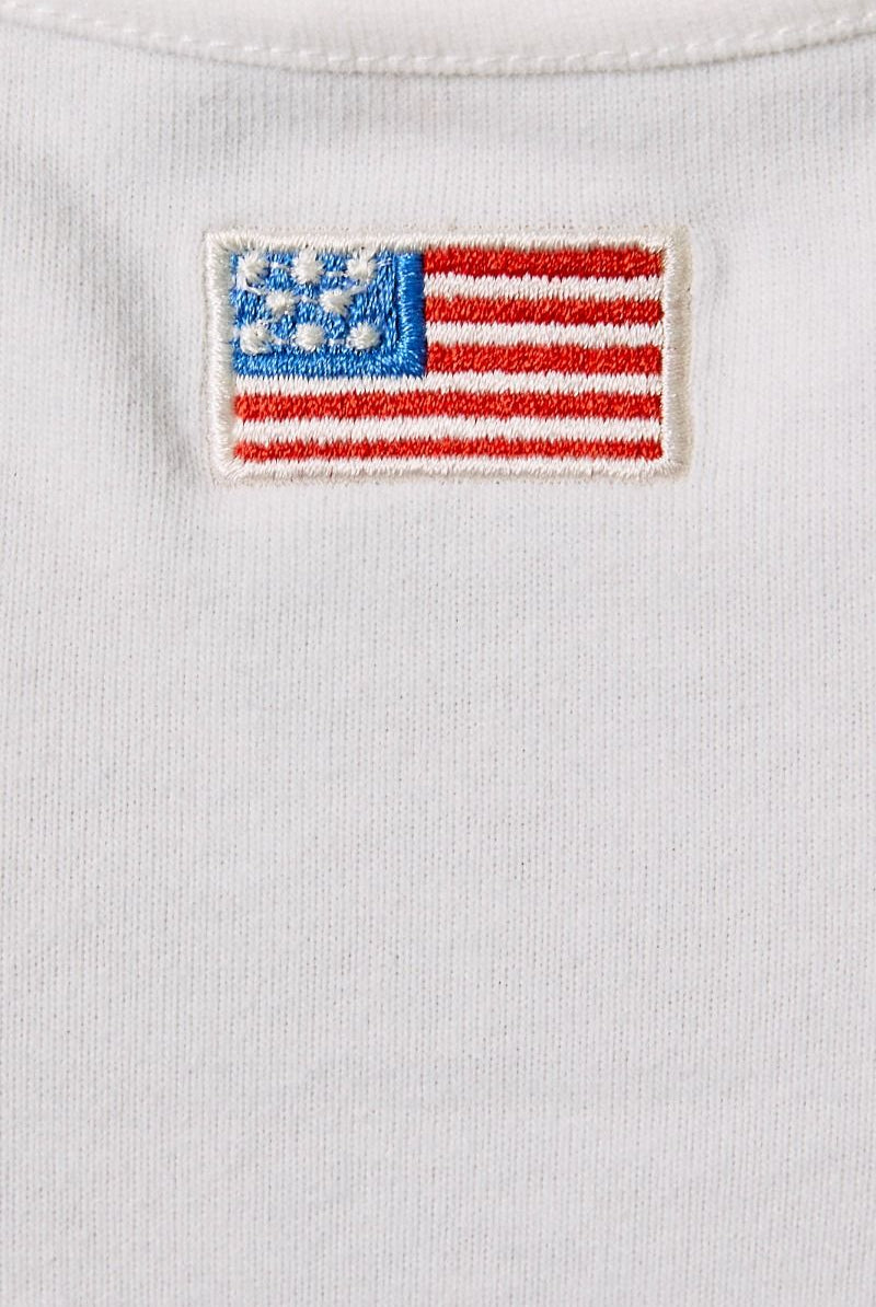 White tank top featuring embroidered American flag patch and halter neck design by Le Lis, styled with casual and patriotic elements.