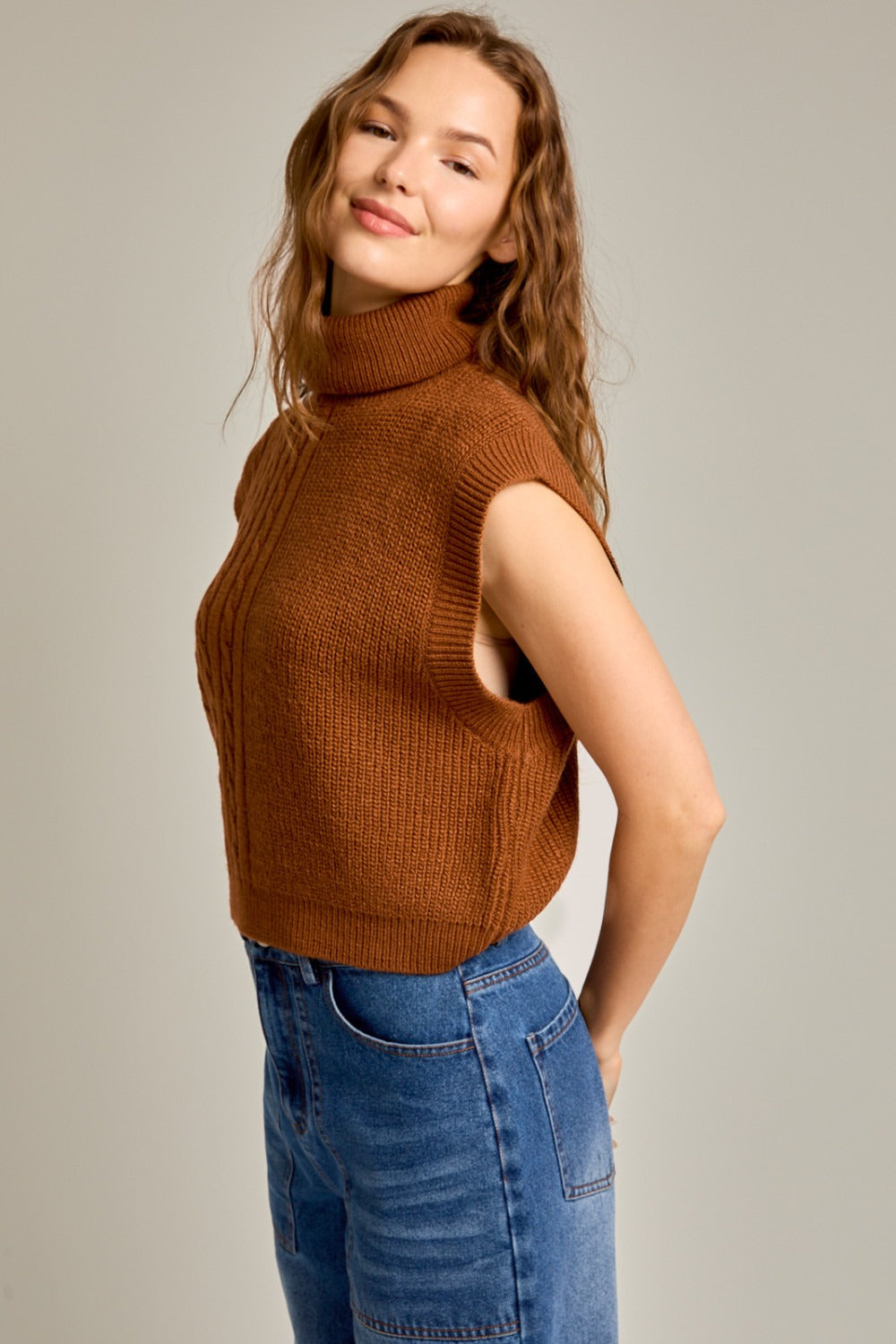 Caramel ribbed and cable knit turtleneck sweater vest by RARA Boutique, featuring a cozy sleeveless design and textured knit pattern.