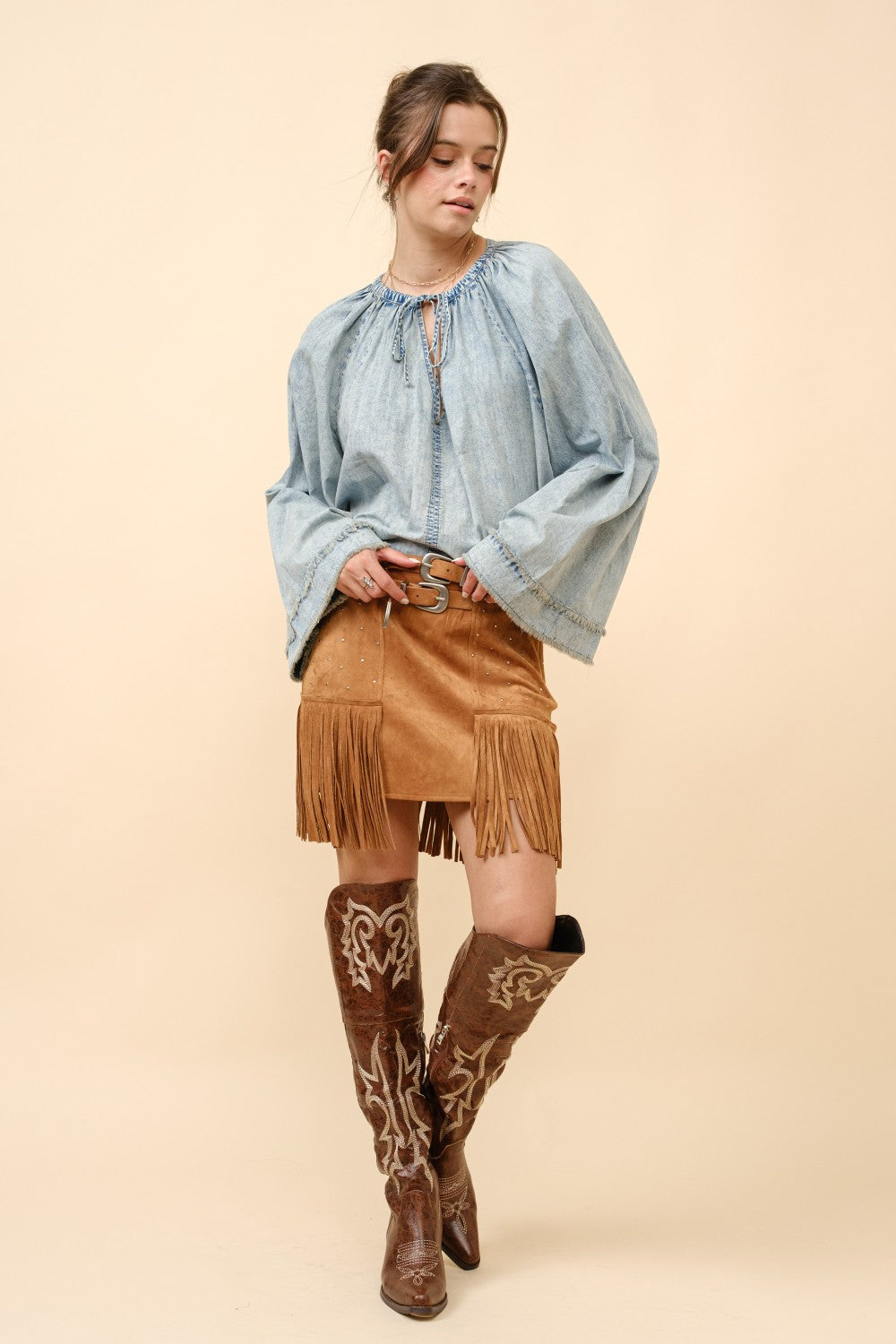Blue suede mini skirt with double belt, star studs, and fringe details from RARA Boutique, styled with a trendy, edgy look.