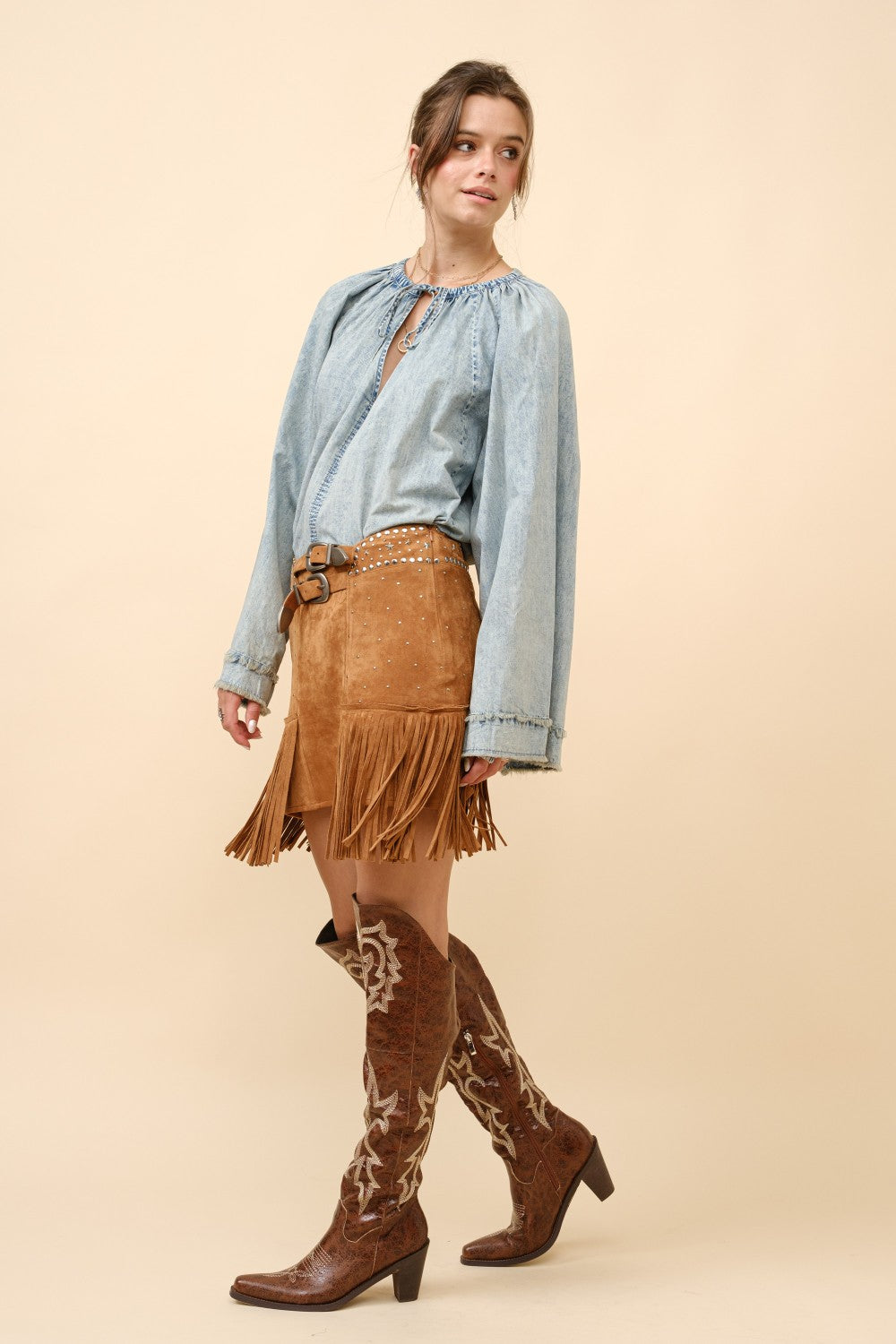Blue suede mini skirt with double belt, star studs, and fringe detail from RARA Boutique, featuring a stylish and edgy design.