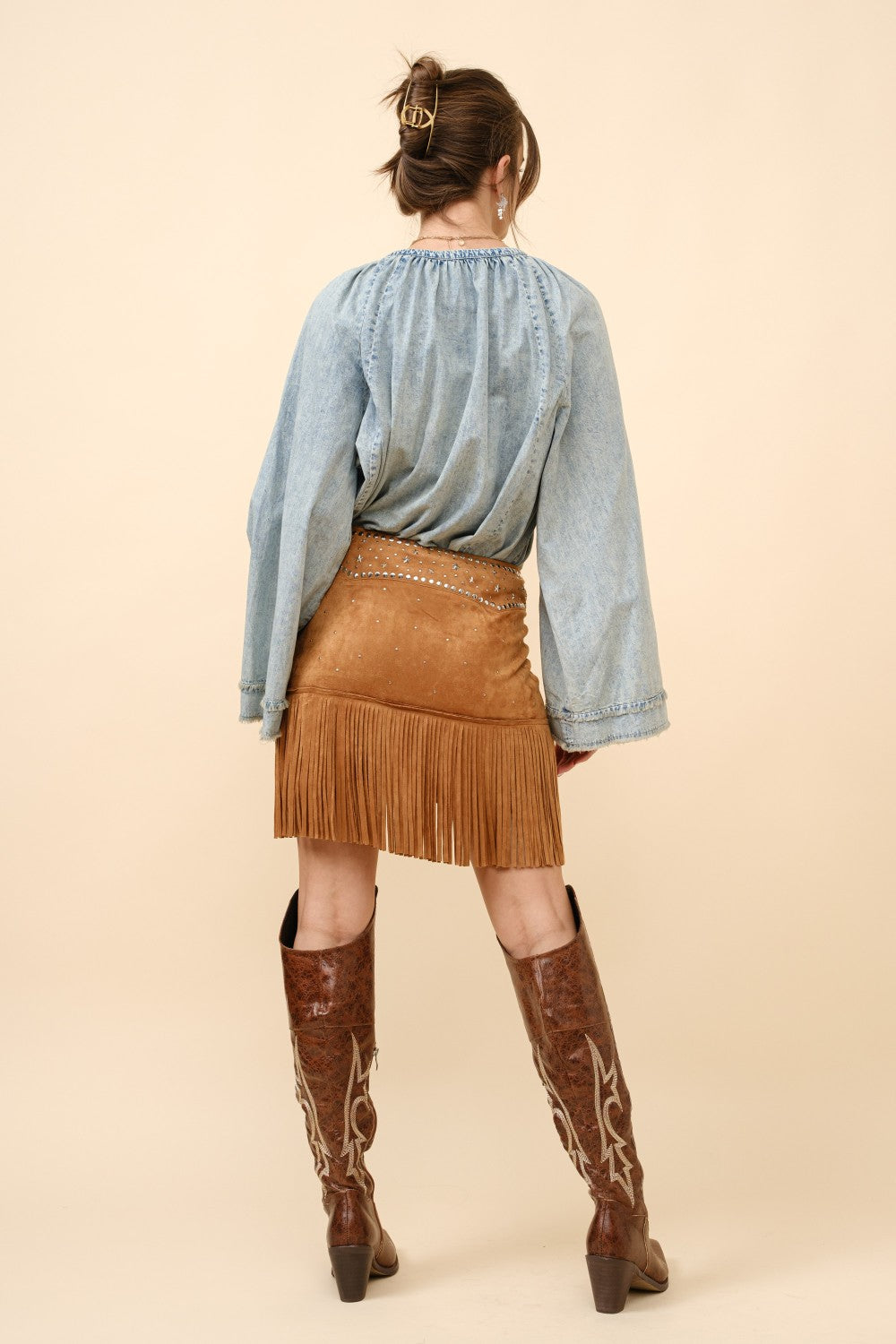 Blue suede mini skirt with double belts, star studs, and fringe detail from RARA Boutique, styled with a trendy, edgy look.