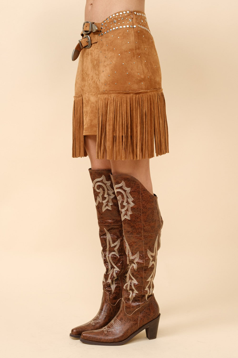 Blue suede mini skirt with double belts, star studs, and fringe detailing by RARA Boutique.