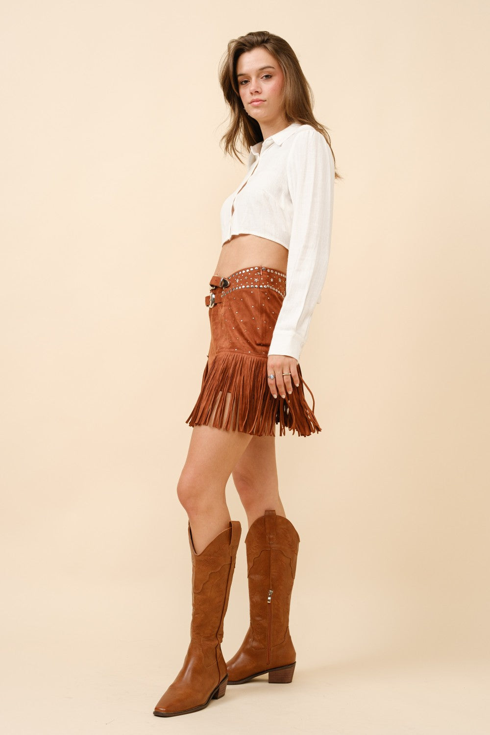 Blue suede mini skirt with double belt, star studs, and fringe details from RARA Boutique, featuring a trendy, stylish design.