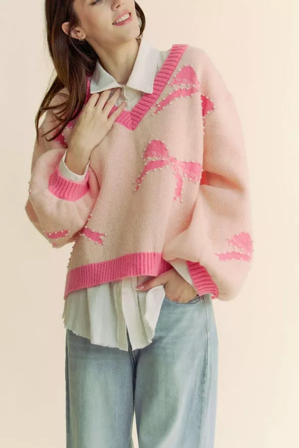 Cream sweater with pearl-studded bow and balloon sleeves, featuring a V-neck design from RARA Boutique.