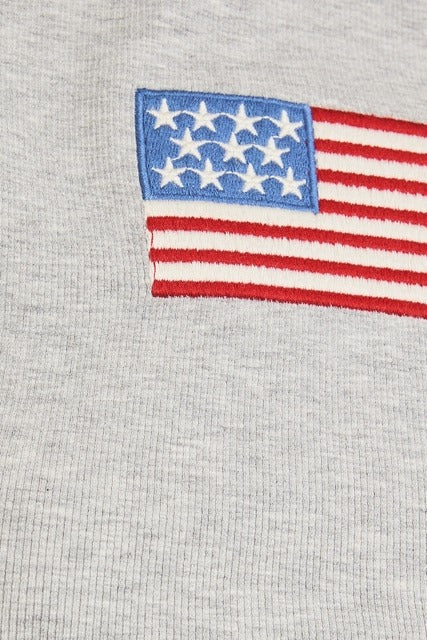 Rara Boutique embroidered American flag ribbed baby tee with short sleeves and patriotic flag design on soft fabric.