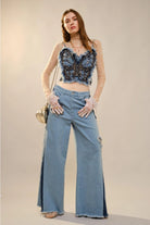 Blue denim blouse with butterfly embellishments, RARA Boutique's stylish corset top featuring a fitted design and decorative details.