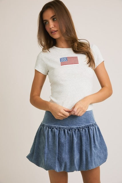 Rara Boutique embroidered American flag ribbed baby tee with short sleeves and patriotic star detail on white fabric.