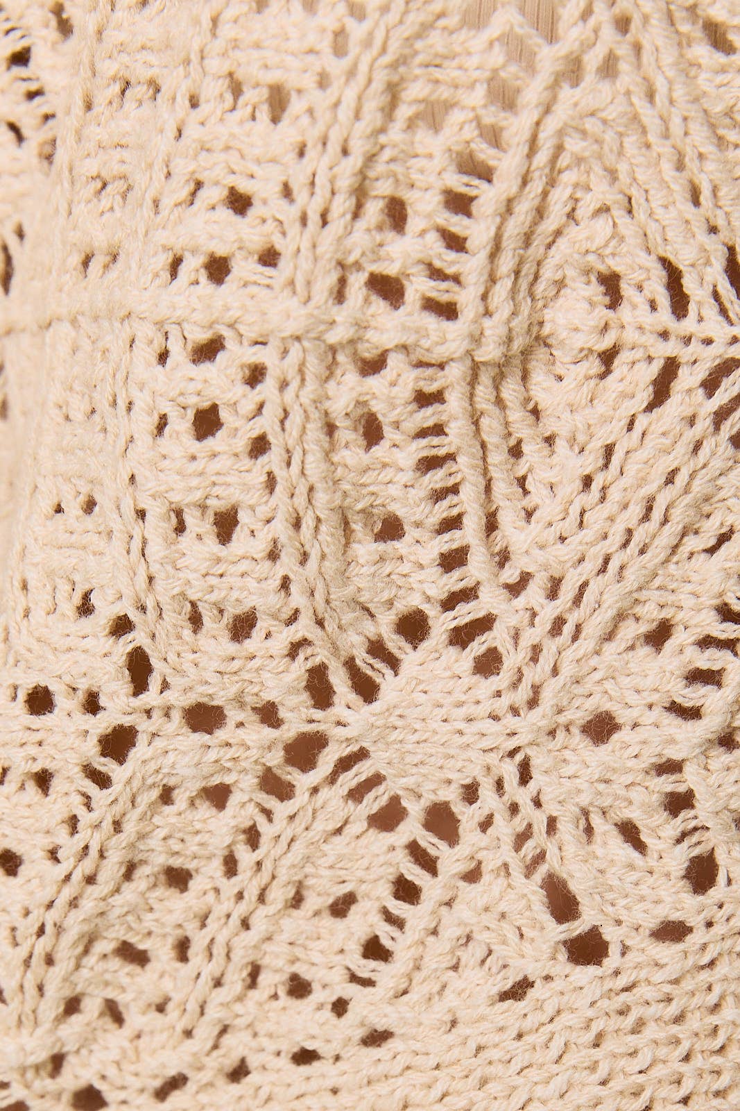 Long sleeve crochet cardigan by LE LIS, featuring intricate knit pattern and button closure, displayed on a neutral background.