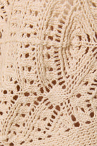 Long sleeve crochet cardigan by LE LIS, featuring intricate knit pattern and button closure, displayed on a neutral background.