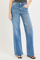Medium wash Risen studded wide-leg high-rise jeans with distressed details and belt loops, displayed on a hanger.