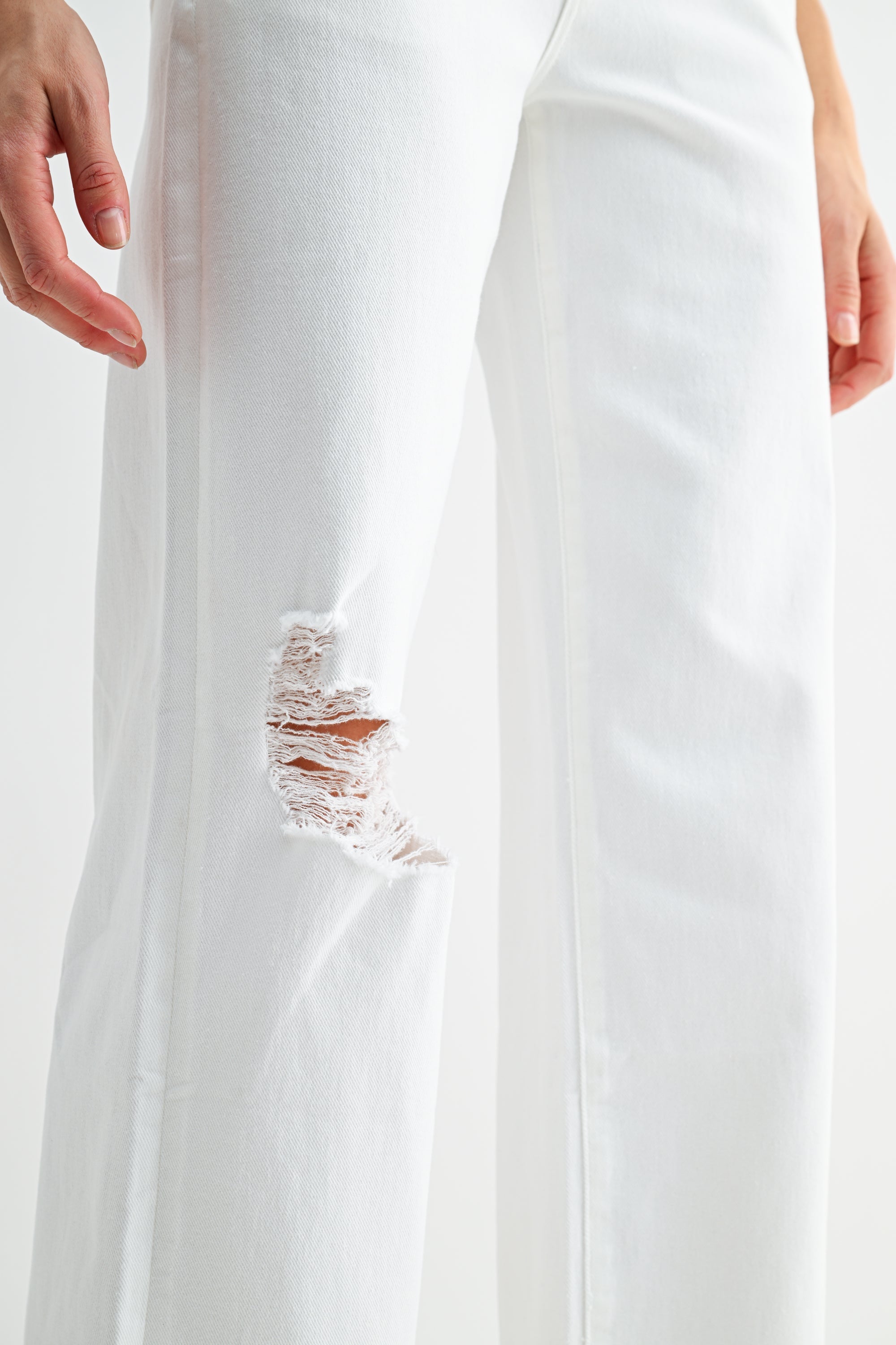 Light wash mid-rise distressed wide leg jeans by RARA Boutique with ripped details and relaxed fit, shown on a model.