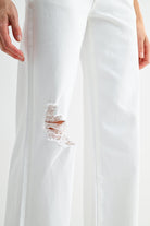 Light wash mid-rise distressed wide leg jeans by RARA Boutique with ripped details and relaxed fit, shown on a model.