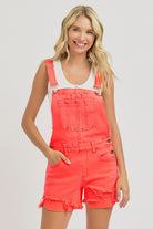 Distressed coral denim overalls by Risen, featuring a casual fit with adjustable straps and rolled cuffs for a trendy look.