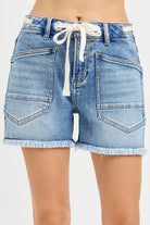 Light blue grommet waist tie cutoff denim shorts from Risen, styled with frayed hems and distressed details.