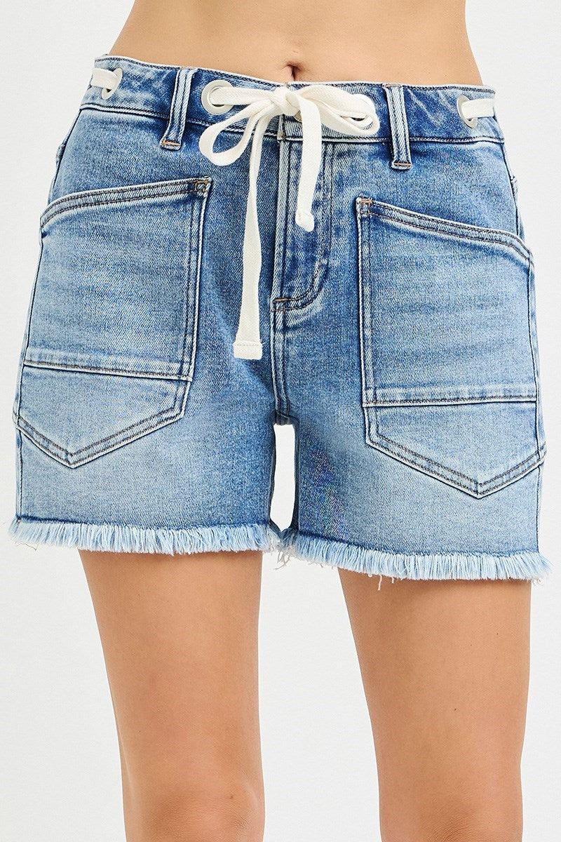 Light blue grommet waist tie cutoff denim shorts from Risen, styled with frayed hems and distressed details.