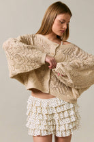 Long sleeve crochet cardigan by LE LIS, featuring detailed knit pattern and open-front design, worn casually over a top.