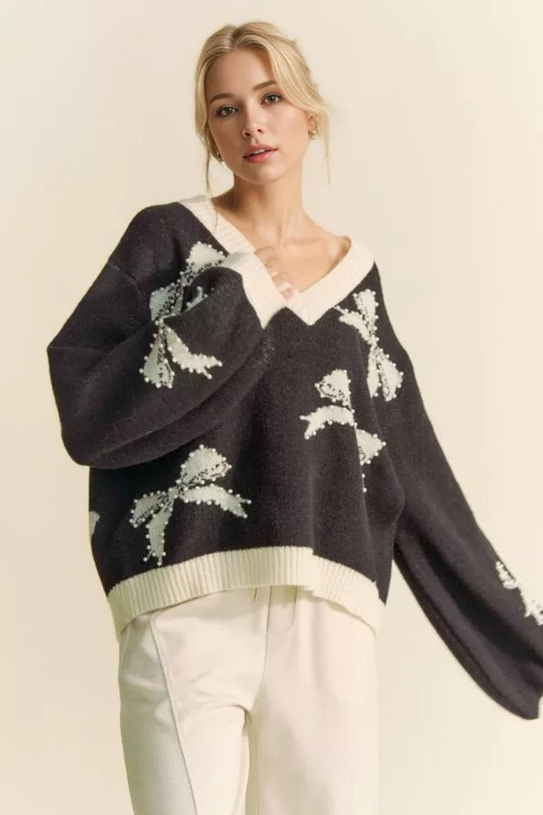 Cream-colored sweater with pearl-studded bow accents, balloon sleeves, and a V-neck, by RARA Boutique.