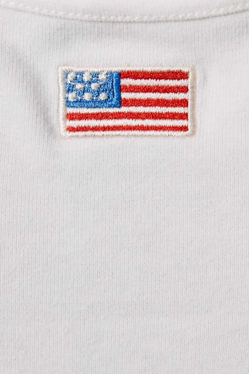 White tank top featuring embroidered American flag patch and halter neck design by Le Lis, styled with casual and patriotic elements.